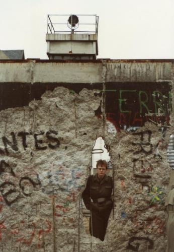 A-Border Guard-looking-forlornly-through-a-hole-in-the-wall-Berlin-89